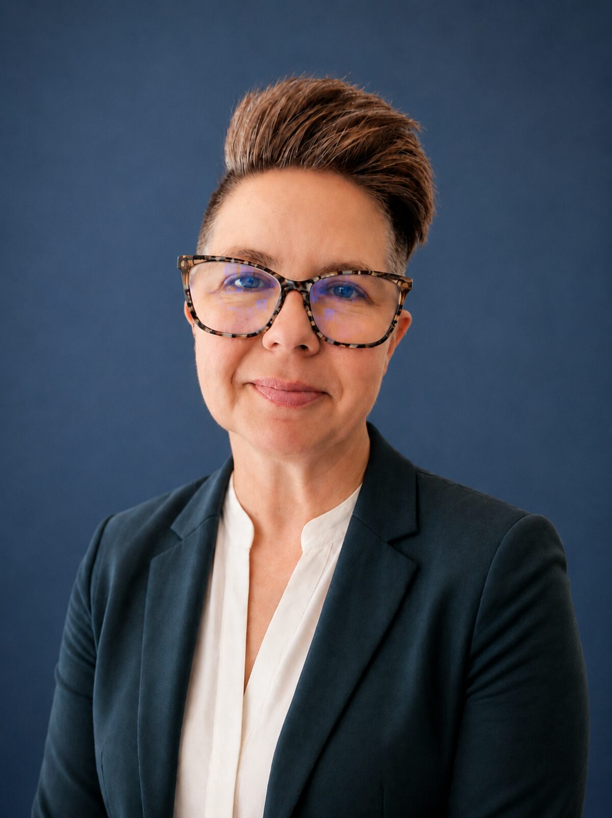 Katie Mayes in a navy blazer against a deep blue backdrop.